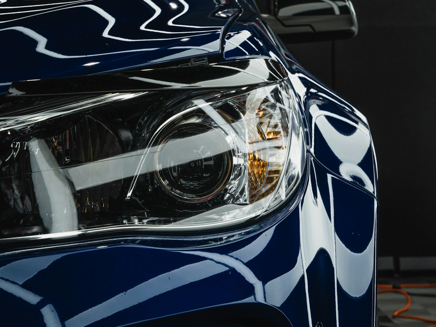 Close-up of a freshly protected glossy car panel and headlight reflecting studio lighting