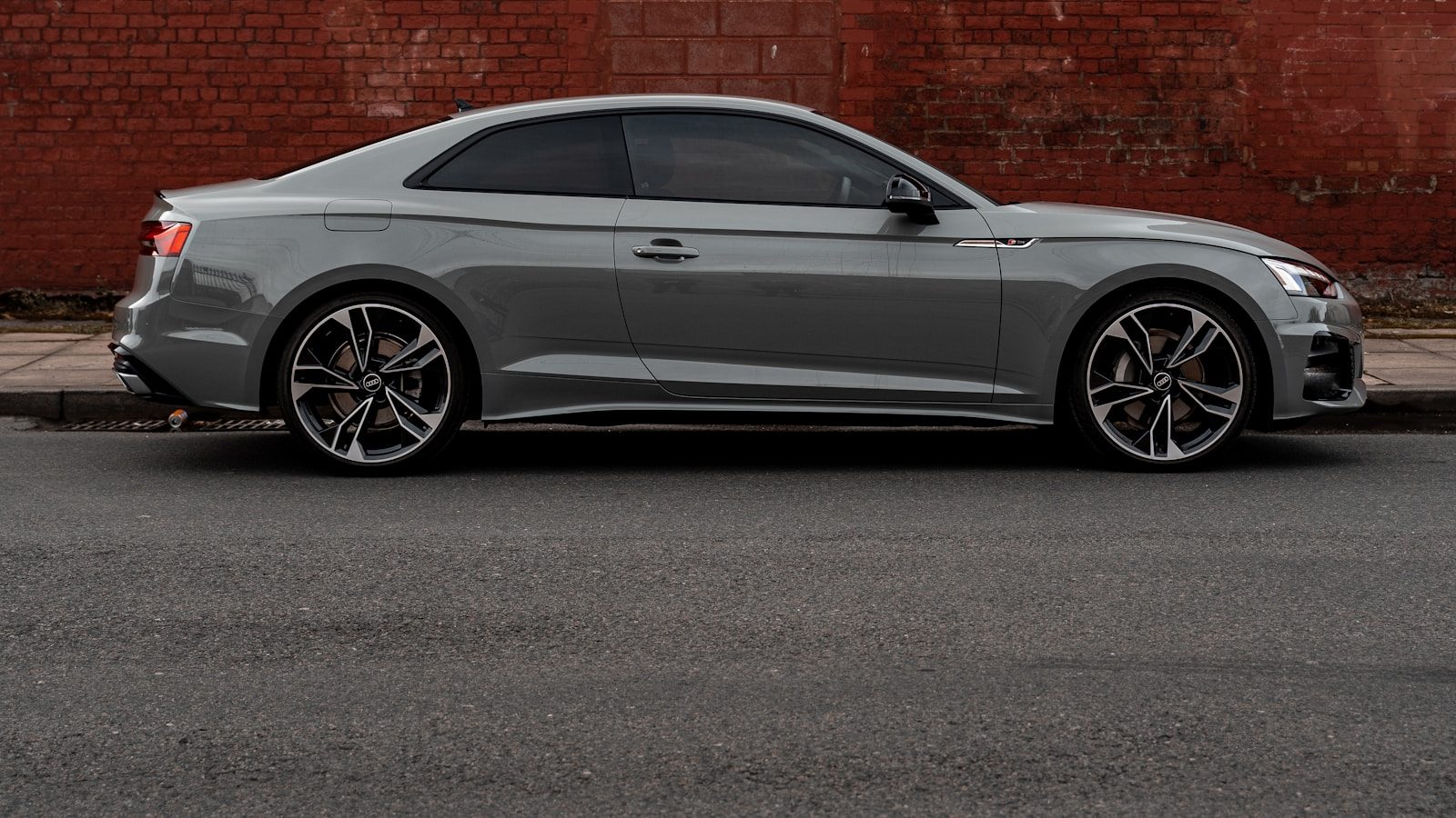Silver coupe in side profile with the front bumper and leading edge of the hood highlighted in teal